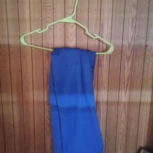 A pair of blue jeans hangs on a green plastic hanger, which is hooked onto a nai